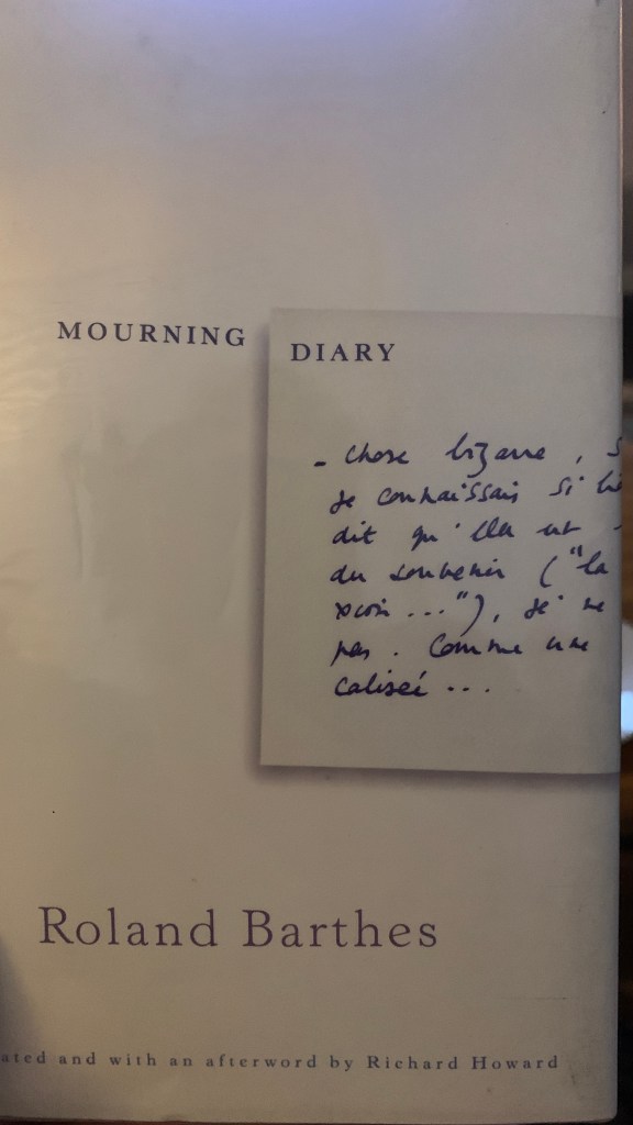 A photo of the book cover Mourning Diary by Roland Barthes. One of the author's original note cards hand written in French is shown, the note cards which comprise the totality of the book described in this blog post.